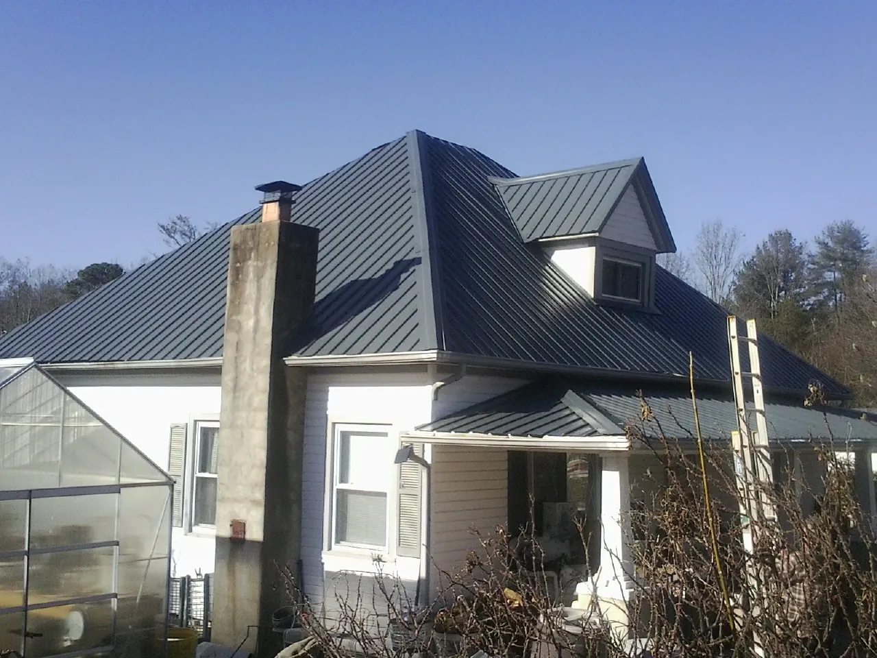Dark blue standing seam metal roof on a white farmhouse with dormer — Slate & Tile Roof Repair by Roofing Brothers in Powhatan Point