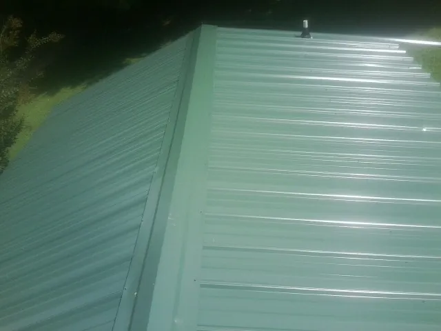 New green metal panels meeting at the ridge of a roof — Flat Roof Repair work by our crew in Powhatan Point
