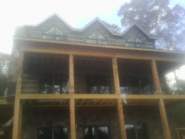 Dormers and porch framing on a large log home under construction — Roof Coating work by our crew in Powhatan Point