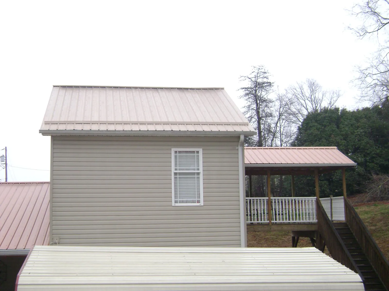 Tan metal roofs on a two story addition and attached porch, from a Roof Replacement job in Powhatan Point
