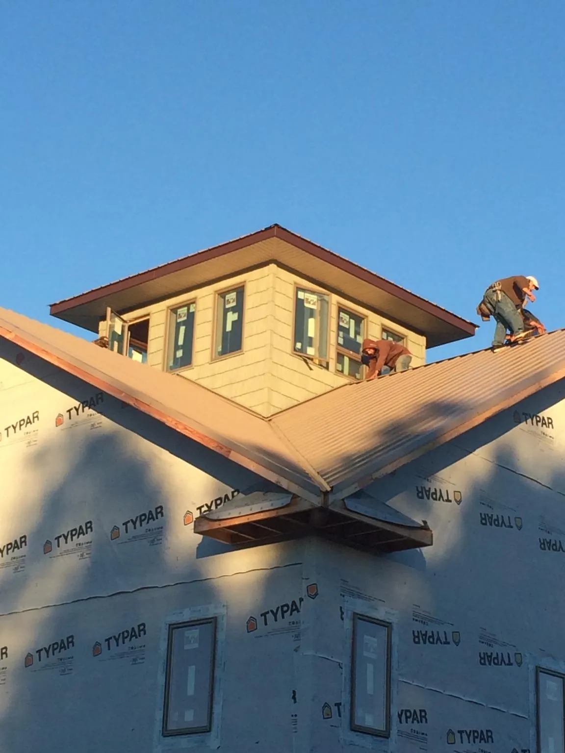 Roofers working around a rooftop cupola on a new metal roof at sunset — Roof Waterproofing in Powhatan Point by Roofing Brothers